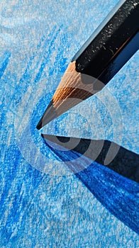 Close-up of a pencil tip on blue textured paper