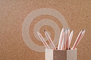 Close up of pencils in wooden holder with brown background