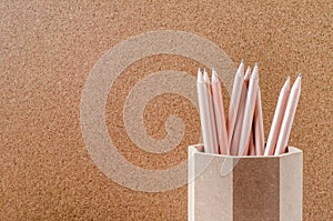 Close up of pencils in wooden holder with brown background