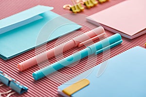 Close up of pens and colorful notebooks on pink.