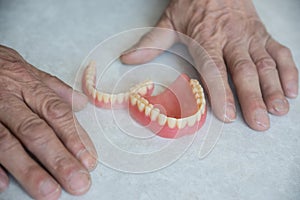 close-up of a pensioner's hand and removable dentures lying on the table, selective focus. problem with teeth,