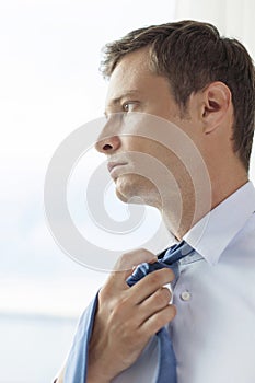 Close-up of pensive businessman loosening necktie in hotel