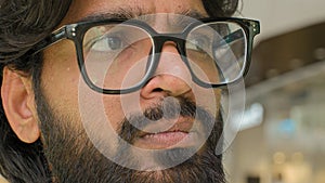 Close up pensive serious male face eyes in glasses looking distance. Bearded Indian Arabian businessman think look to