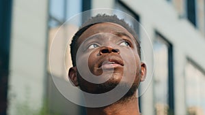 Close up pensive thinking ethnic man looking around outdoor business student guy look up on urban building think