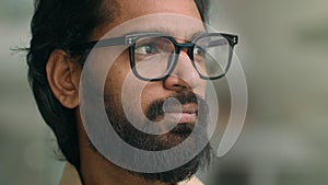 Close up pensive thoughtful calm Indian man in eyeglasses spectacles thinking dreaming looking to side. Portrait serious