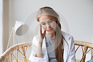 Close-up pensive woman sitting in a chair holding her head emotional stress, problems in relationships