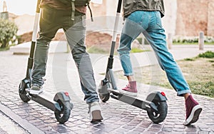 Close up of people couple using electric scooter in city park - Millenial students riding new modern ecological mean of transport photo