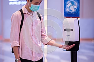 Close up people hands using wash hand automatic alcohol gel dispenser to sanitize and disinfect Coronavirus COVID-19  pathogens photo