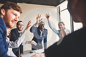 Close-up of people holding hands together while sitting around the desk