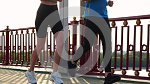 Close up of people legs in sportswear running on street outdoors on bridge. Man and woman legs jogging. Male and female