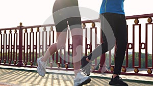 Close up of people legs in sportswear running on street outdoors on bridge. Man and woman legs jogging. Male and female