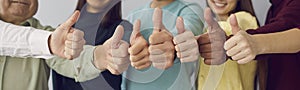 Close up of people showing raised thumbs at camera as gesture of recommendation or good choice.