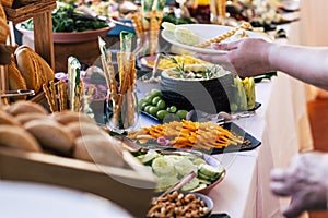 Close up of people taking food from table at event party with catering self service