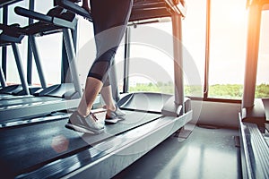 Close up of people who exercising on treadmill. Close-up of woman legs walking by treadmill in sports club. Fitness and Body