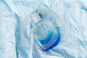 Close up of perfume bottle on blue background, tiny and delicate fabric with water drops. top view. beauty concept