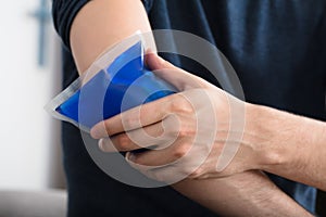 Person Applying Ice Gel Pack On An Injured Elbow photo