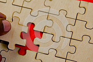 Close up of a person completing a jigsaw puzzle with missing piece