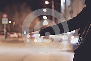 close up person hand hitch-hiking and waiting for a car stand on a highway in the night f