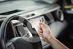 Close up person hand holding the driver license in front of the steering wheel