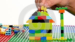 Close up of person hand making a house with colorful lego blocks.