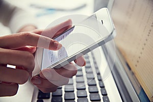 Close Up Of Person At Laptop Using Mobile Phone photo