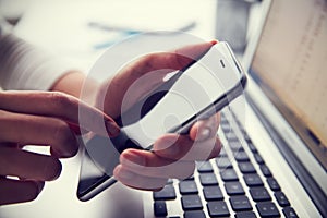 Close Up Of Person At Laptop Using Mobile Phone