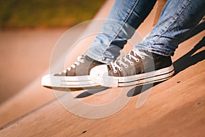 A close up of a person in a pair of jeans and a pair of lace up deck shoes