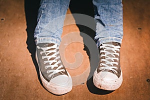 A close up of a person in a pair of jeans and a pair of lace up deck shoes