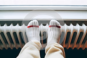 Close up of person\'s feet with socks put on heating radiator to warm up during winter