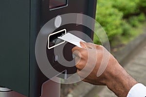 Close-up Of Person`s Hand Inserting Ticket Into Parking Meter