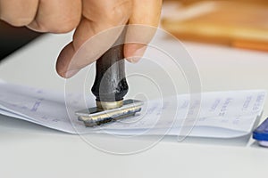 Close-up Of Person`s Hand Stamping On Approved Application Form or Notary public in office documents for signing approval.