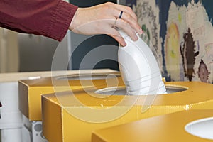 Close-up of a person\'s hand throwing a used plastic bottle into special container for collecting recyclable waste