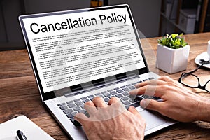 Man Reading Cancellation Policy Agreement On Laptop At Office photo