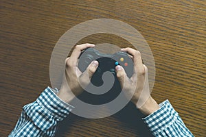 Close up person`s hands playng video game isolated on wooden table concept