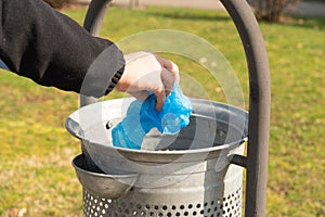 Close-up of person throwing away shoe covers in trash can