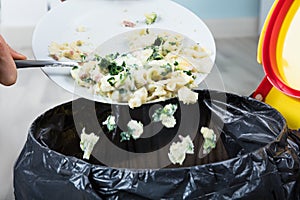 Person Throwing Cooked Pasta In Trash Bin photo