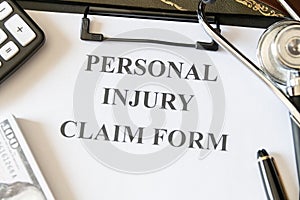 Close-up of a personal injury claim form with a stethoscope, calculator, and cash, indicating healthcare expenses.