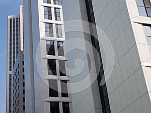 Close up perspective detail of a row of tall high rise modern apartment buildings with geometric white cladding and dark windows