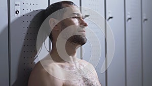 Close-up of perspiring handsome sportsman wiping sweat with white towel. Portrait of tired Caucasian man resting after