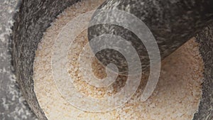 Close-up of pestle mixing lemon zest and brown sugar and salt in a stone mortar