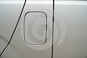 A close up of a petrol cap cover on a modern white car, car\'s fuel tank lid