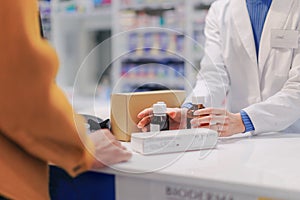 Close up of pharmacist selling medications to the customer.