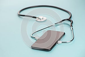 Close-up on a phone with a stethoscope on blue background