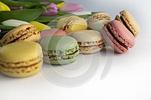 Close up phot of sweet macarons and spring tulip flowers on white background