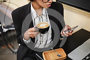 Z blízka z americký na stôl z kaviareň mobil a pohár z káva v ruky. dáma 