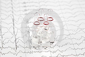 Close-up photo of ampoules with medicine on EKG graph