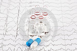 Close-up photo of ampoules with medicine and pills on EKG graph