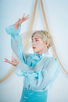 close up photo of an Asian woman with short blonde hair and wearing a blue dress