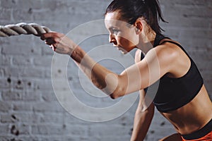 Close up photo of Athletic woman doing battle rope exercises at gym