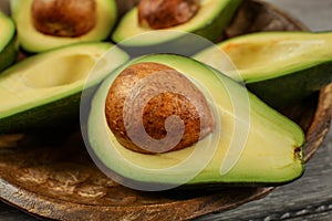 Close up photo of avocado halves on wooden carved bowl, detail o